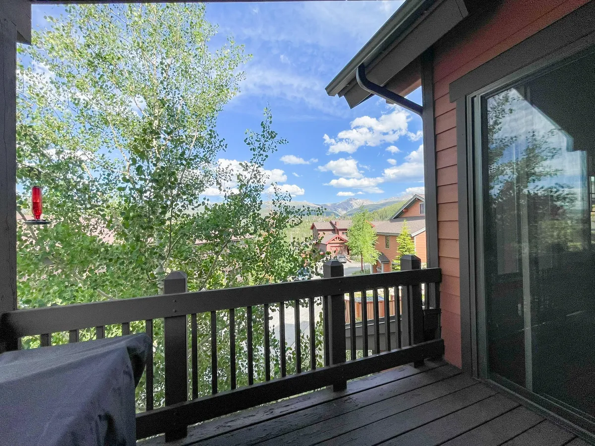 A serene balcony overlooks rolling mountains, treetops, and clouds, with a simple railing framing the picturesque landscape. It evokes a sense of peacefulness and connection to the outdoors, inviting moments of relaxation and exploration.