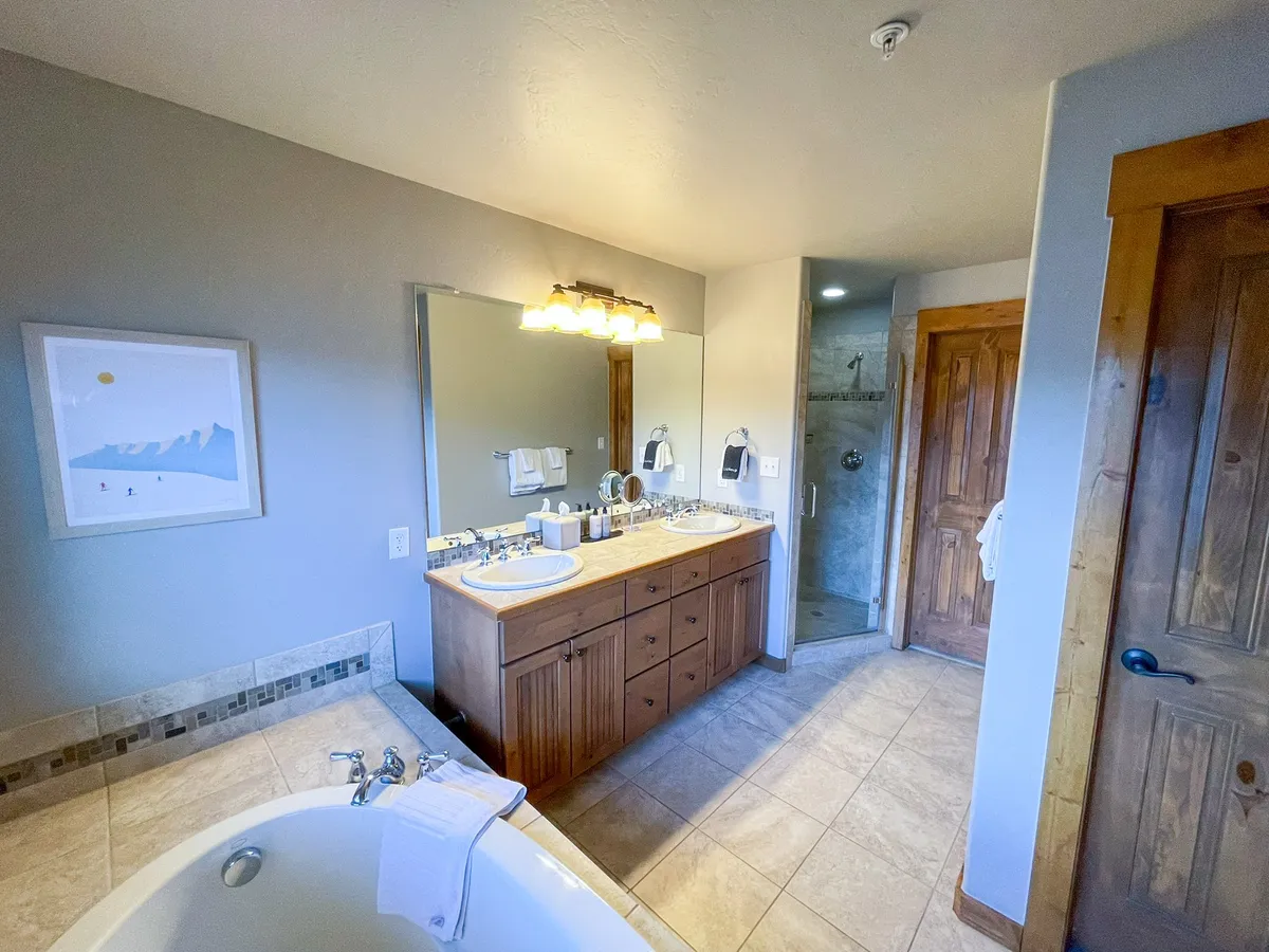 A luxurious ensuite bathroom with a double vanity, large mirror, bathtub, and walk-in shower. The serene decor and well-appointed fixtures create a spa-like retreat for relaxation and self-care.