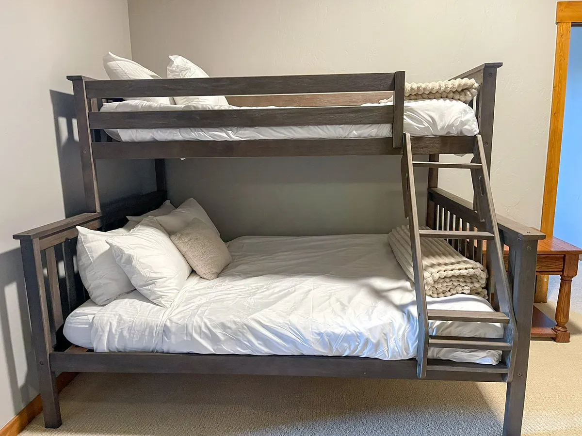 A playful bunk bed setup complete with pillows and a sturdy ladder, ideal for children or groups. The ambiance is cheerful and inviting, encouraging nighttime stories and sibling bonding.